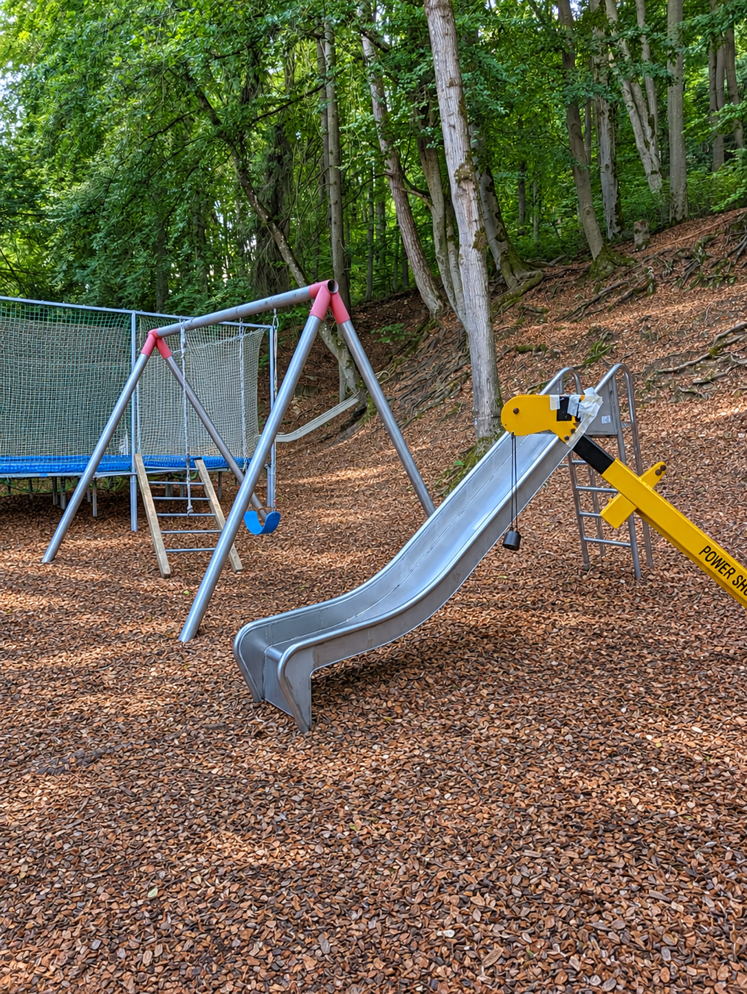 Übersicht des Spielplatzes mit Rutschen, Schaukeln und Trampolin